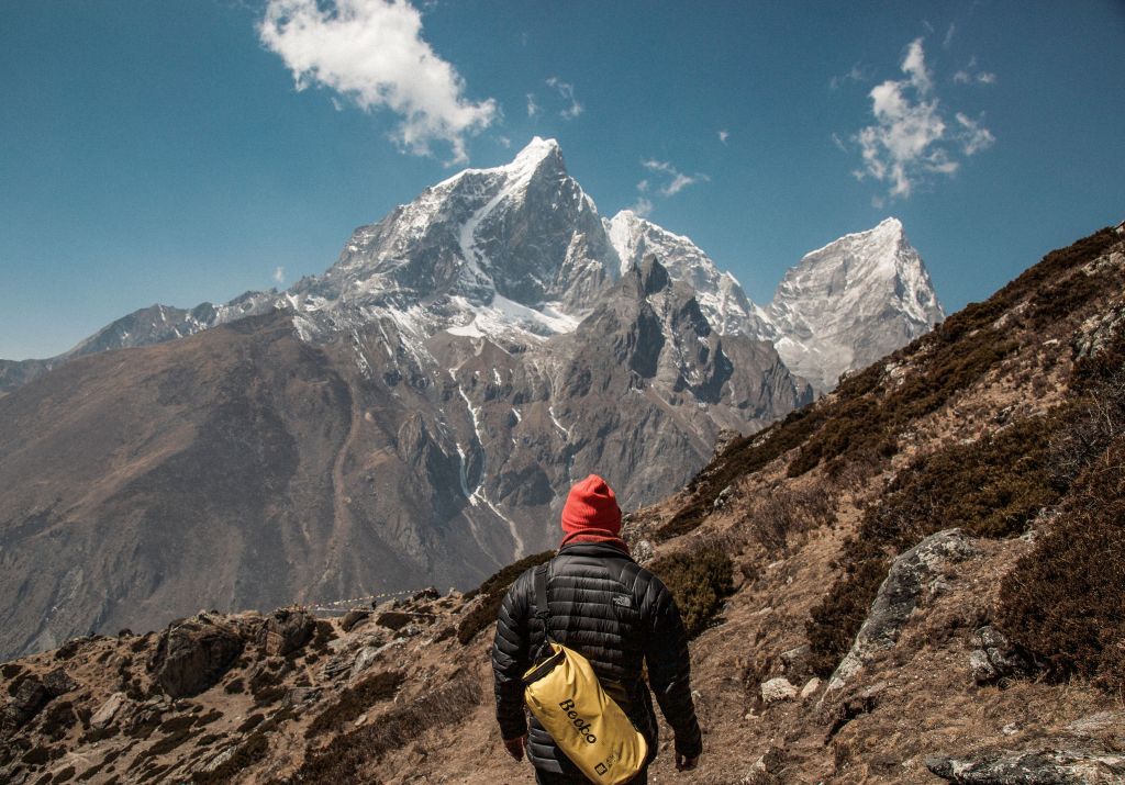 Person with back pack about to climb a mountain.
