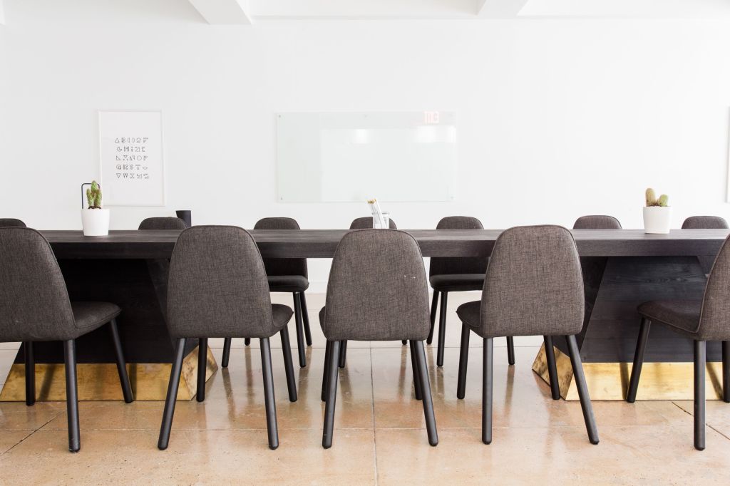A minimalist modern office meeting room featuring a long table with chairs and neat decoration
