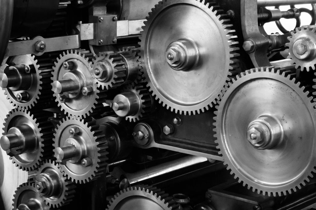 This image shows a close-up of interlocking gears and cogs within machinery, highlighting the intricate details and mechanical complexity of industrial engineering components.